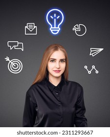 Young woman with many icons and glowing bulb over head. Over gray background. - Shutterstock ID 2311293667