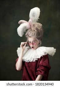 Young woman as Marie Antoinette isolated on dark green background. Retro style, comparison of eras concept. Beautiful female model like classic historical character, old-fashioned.