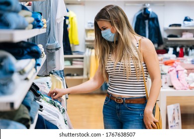 Young Woman In Mask Shopping At A Clothing Store In The Coronavirus Pandemic