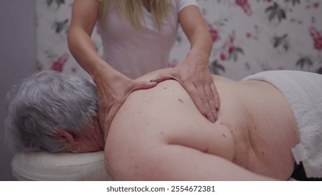 Young woman massaging elderly woman_s back. Physiotherapist providing relaxing massage therapy to senior person, health and wellbeing concept - Powered by Shutterstock