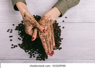Young woman massaging a hand with coffee scrub, top view
