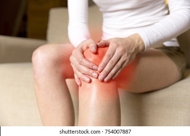 A young woman massaging her painful knee