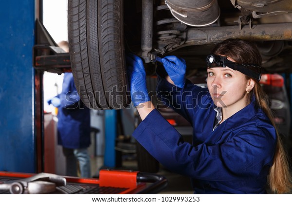 Young woman master is repairing car in\
workshop at workplace\
