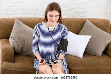 Young Woman Measuring Her Blood Pressure At Home