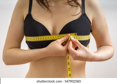 Young woman is measuring her breast size with a tape.