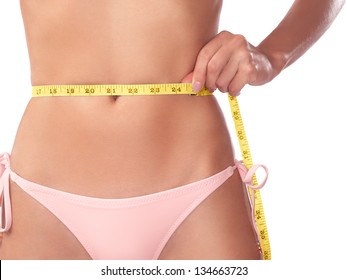 Young woman measuring her waist with a measuring tape, closeup of stomach isolated on white background - Powered by Shutterstock