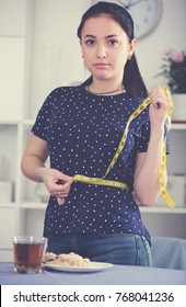 Young Woman Measuring Waist At Home Worried About Weight Gain