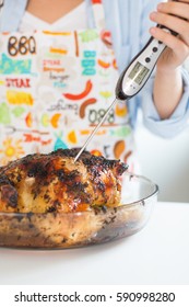 Young Woman Measuring Whole Roasted Chicken Temperature With Digital Meat Thermometer 