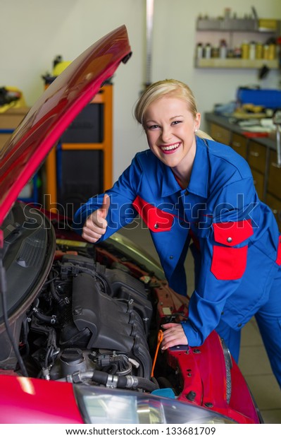 a young woman as a\
mechanic in a garage. rare professions for women. car is being\
repaired in the workshop