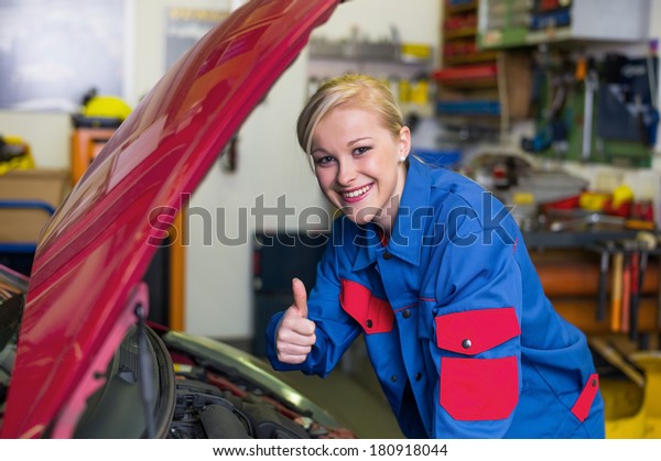 a young woman as a\
mechanic in a garage. rare professions for women. car is being\
repaired in the workshop