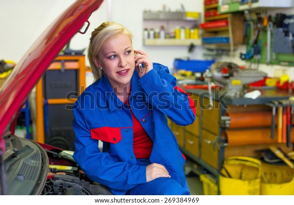 a young woman as a\
mechanic in a garage. rare professions for women. car will be\
repaired in the workshop