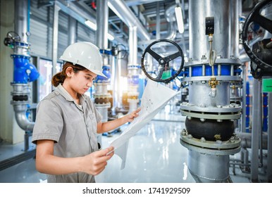 Young Woman Mechanical Engineer Holding Drawing To Checking And Inspection Of HVAC Heating Ventilation Air Conditioning System On Pressure Gauge Of Industrial Air Compressor Boiler Pump Room System
