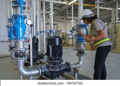 Young woman mechanical engineer inspection heating system on pressure gauge of industrial air compressor pump system at air compressor pump room in the factory