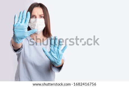 Young woman in medical disposable mask and blue latex gloves on a gray-blue background. Emotion of fright, fear. The concept of the fight against the virus, influenza, pandemic, pneumonia, covid-19