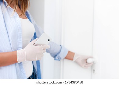 Young Woman In Medical Gloves Holding Mobile Phone. Female Hands Open Or Close Door. Girl Touches Door Handle. Disease Prevention During Quarantine, Health Care. Lifestyle Moment. Close Up.