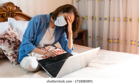 Young Woman In Medical Mask After Online Work At Home Tired Sitting On Bed