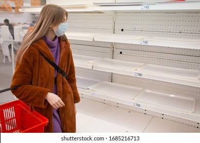 Young Woman In Medical Mask And Empty Shelves In Supermarket