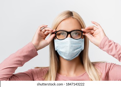 Young Woman In Medical Mask Holding Misted Eyeglasses Isolated On Grey