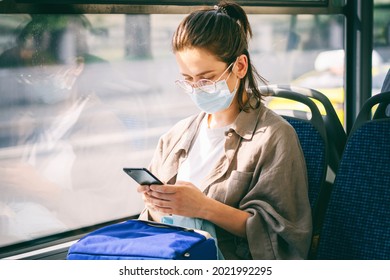 Young Woman In Medical Mask Sitting In Public Bus And Reading News In Smartphone Online