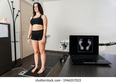 Young woman in a medical office specializing in posturology with her feet on a platform to analyze the pressure exerted and the biomechanical study of footfall