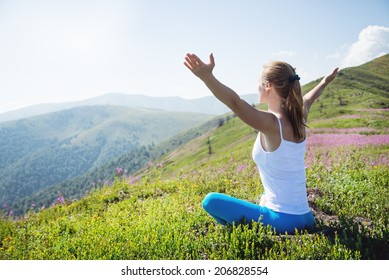 Mujer joven medita en la cima de la montaña en el amanecer