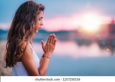 Young woman meditating with her eyes closed, practicing Yoga with hands in prayer position. 