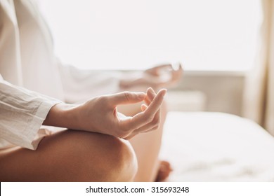 Young woman meditating in the lotus pose at home. Girl doing exercises, practicing yoga indoors. Harmony, yoga practice, balance, meditation, relaxation at home, healthy lifestyle, mindfulness concept - Powered by Shutterstock