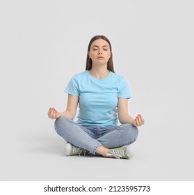 Young woman meditating on light background - Shutterstock ID 2123595773