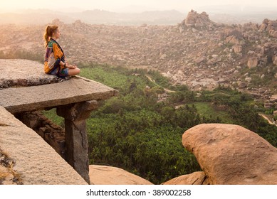 Young Woman Meditating Over Ancient City Landscape On Sunrise In Hampi, India. Copy Space