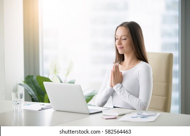 Young Woman Meditating Sitting At The Modern Office Desk In Front Of Laptop, Taking A Pause, Busy, Stressful Office, Cure For Work Overload, One Moment Meditation, Worshiping Laptop 