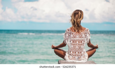 Young Woman Meditation In A Yoga Pose At The Beach