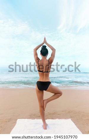 Young woman meditation in a yoga pose at the beach. Girl practices yoga
