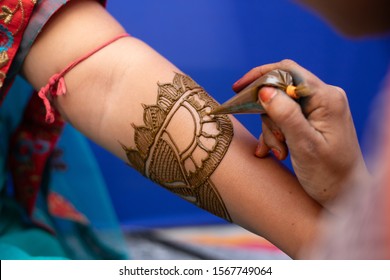 Young Woman Mehendi Artist Painting Henna On Bride's Hand Before Wedding Day