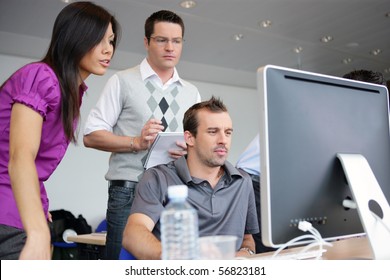 Junge Frauen und junge Männer vor einem Desktop-Computer