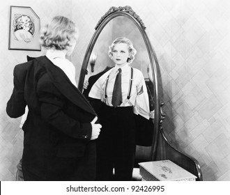 Young woman in men's clothing getting undressed in front of a mirror