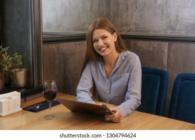 Young woman with menu sitting in restaurant - Shutterstock ID 1304794624