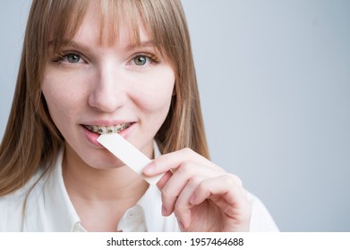 Young Woman With Metal Braces On Her Teeth Is Chewing Gum. The Girl Is Eating Gummy Candy