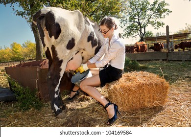 Young Woman Milking Cow On Farm