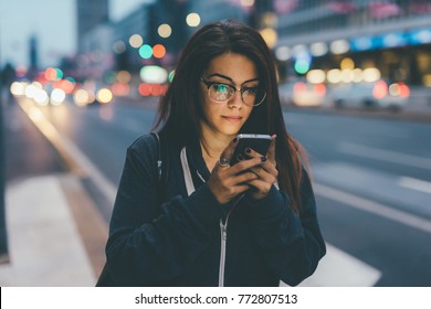 young woman mixed race outdoor night using smart phone face illuminated by screenlight - internet, social network, technology concept - Shutterstock ID 772807513