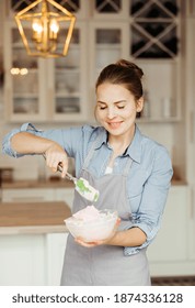 Young Woman Mixes Cake Cream Using A Spatula
