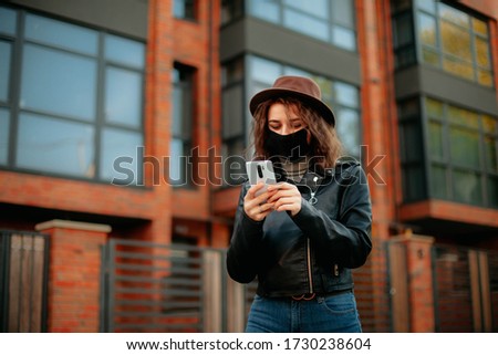 young woman with mobile phone in the city in mask. coronavirus. covid-19. 