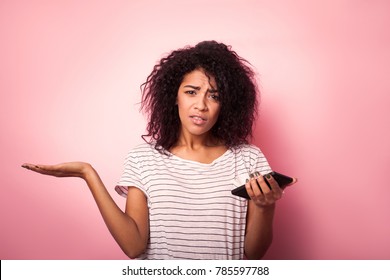 Young Woman With Mobile Phone Confused Isolated On Pink Backgrou