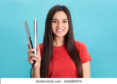 Young Woman With Modern Hair Iron On Blue Background