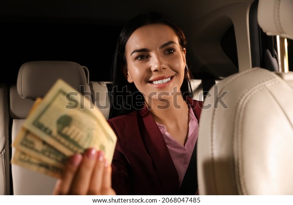 Young woman with money in\
modern taxi