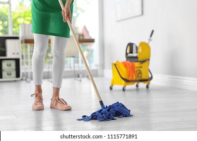 Young Woman With Mop Cleaning Floor In Office