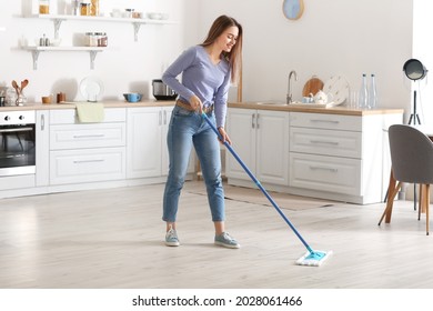 Young woman mopping floor in kitchen - Powered by Shutterstock