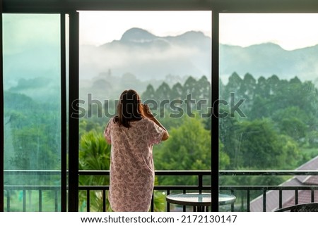 Young woman with morning landscape from the bedroom.