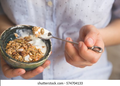 Young Woman With Muesli Bowl. Girl Eating Breakfast Cereals With Nuts, Pumpkin Seeds, Oats And Yogurt In Bowl. Girl Holding Homemade Granola. Healthy Snack Or Breakfast In The Morning.