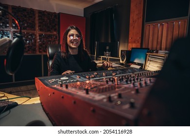 Young Woman Music Producer Working On A Mixing Soundboard While In Her Studio