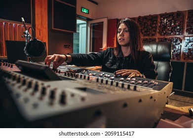 Young Woman Music Producer Working On A Mixing Soundboard While In Her Studio